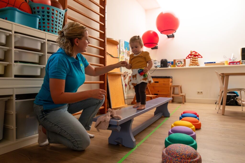 Peuter loopt over de houten bank met Mineke